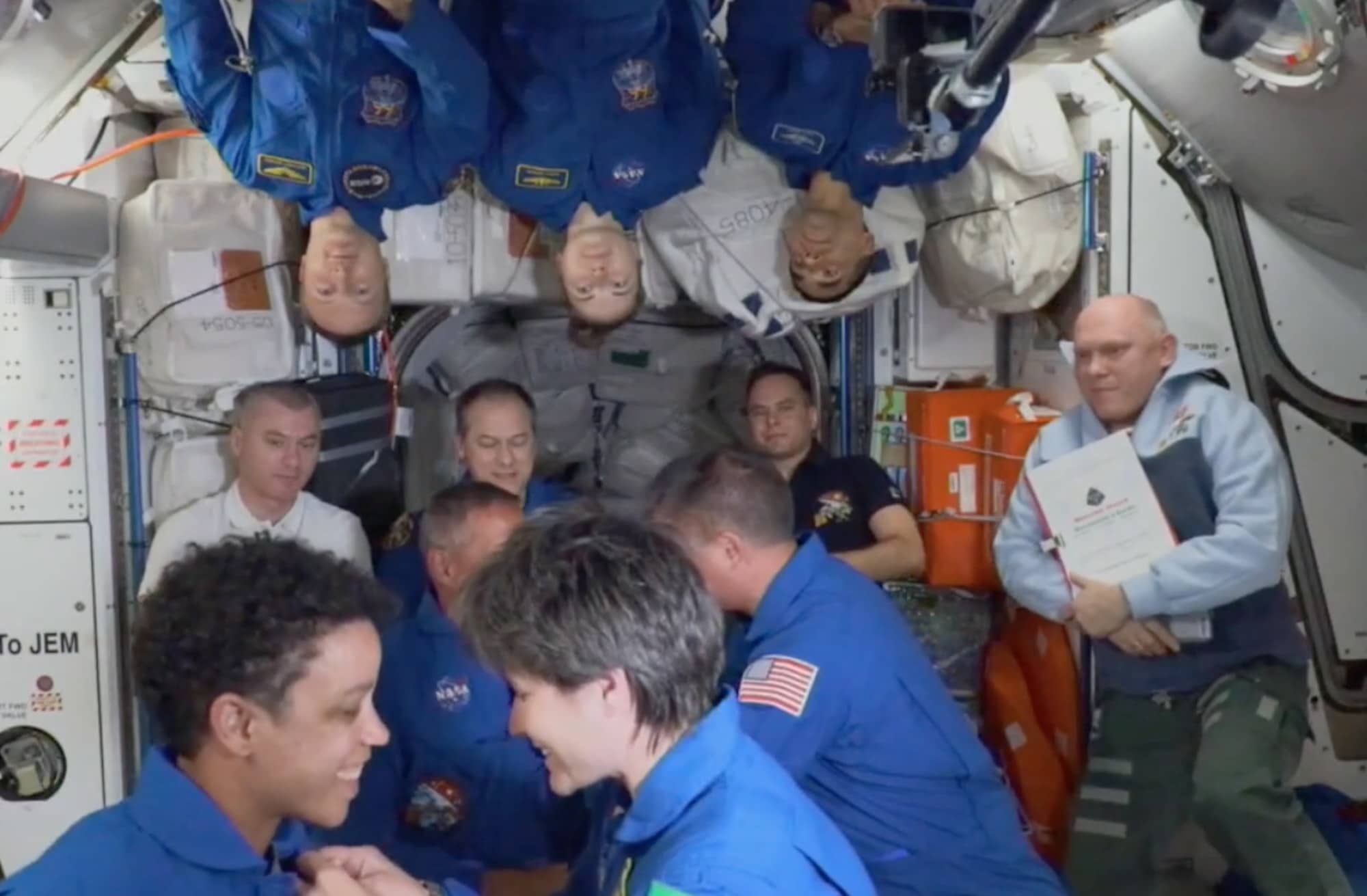 En bas, on voit Samantha Cristoforetti de l’ESA remettre ses ailes d’astronautes à Jessica Watkins de la NASA qui partait pour la première fois sur orbite. En haut à gauche, Matthias Maurer également de l’ESA. Crédit : Cité de l’espace/capture NASA TV recadrée