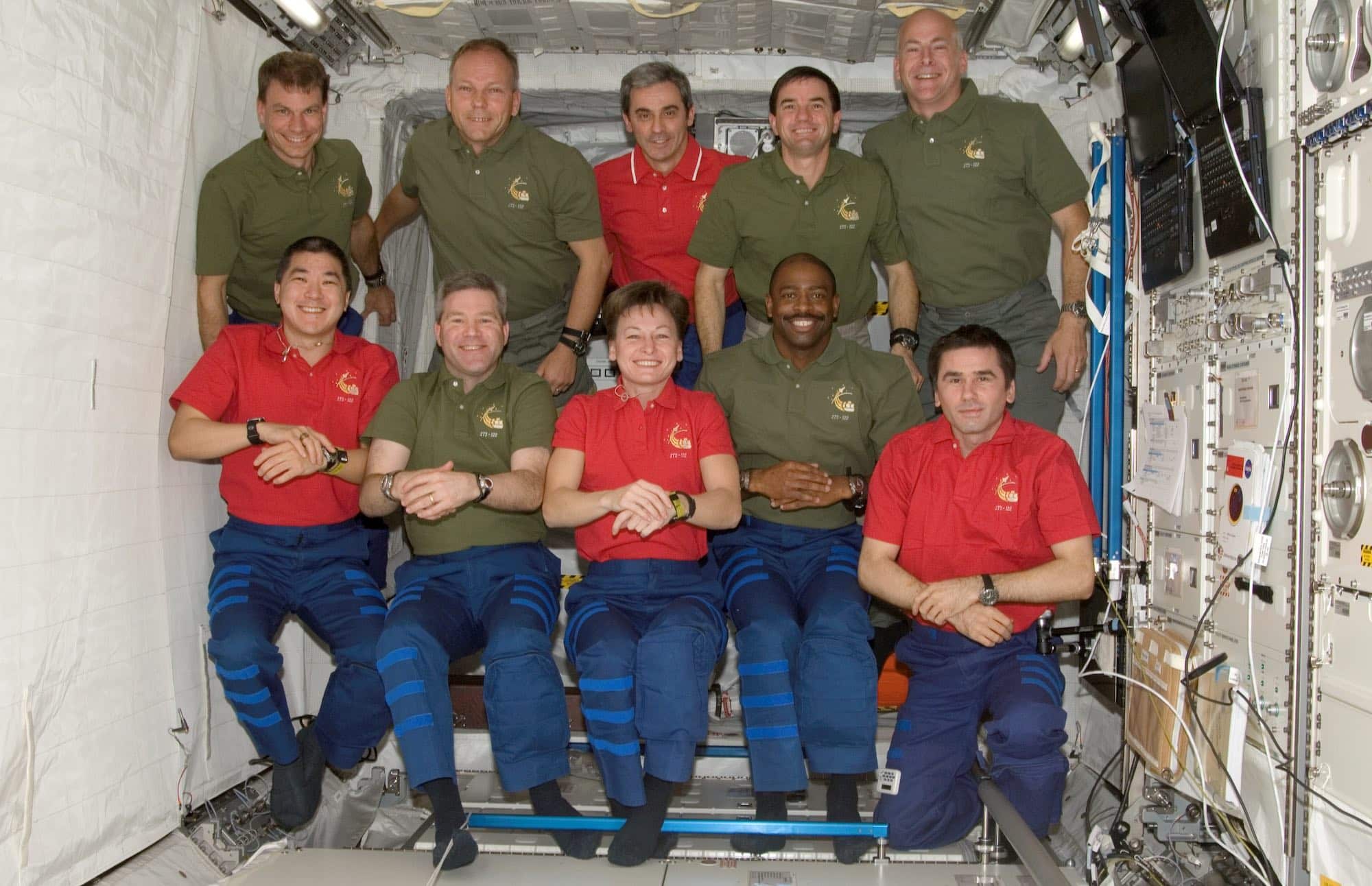 Les équipages de l’ISS et de la navette réunis dans le module européen Columbus. En haut, deuxième à partir de la gauche : Hans Schlegel avec Léopold Eyharts en rouge à côté. Crédit : NASA