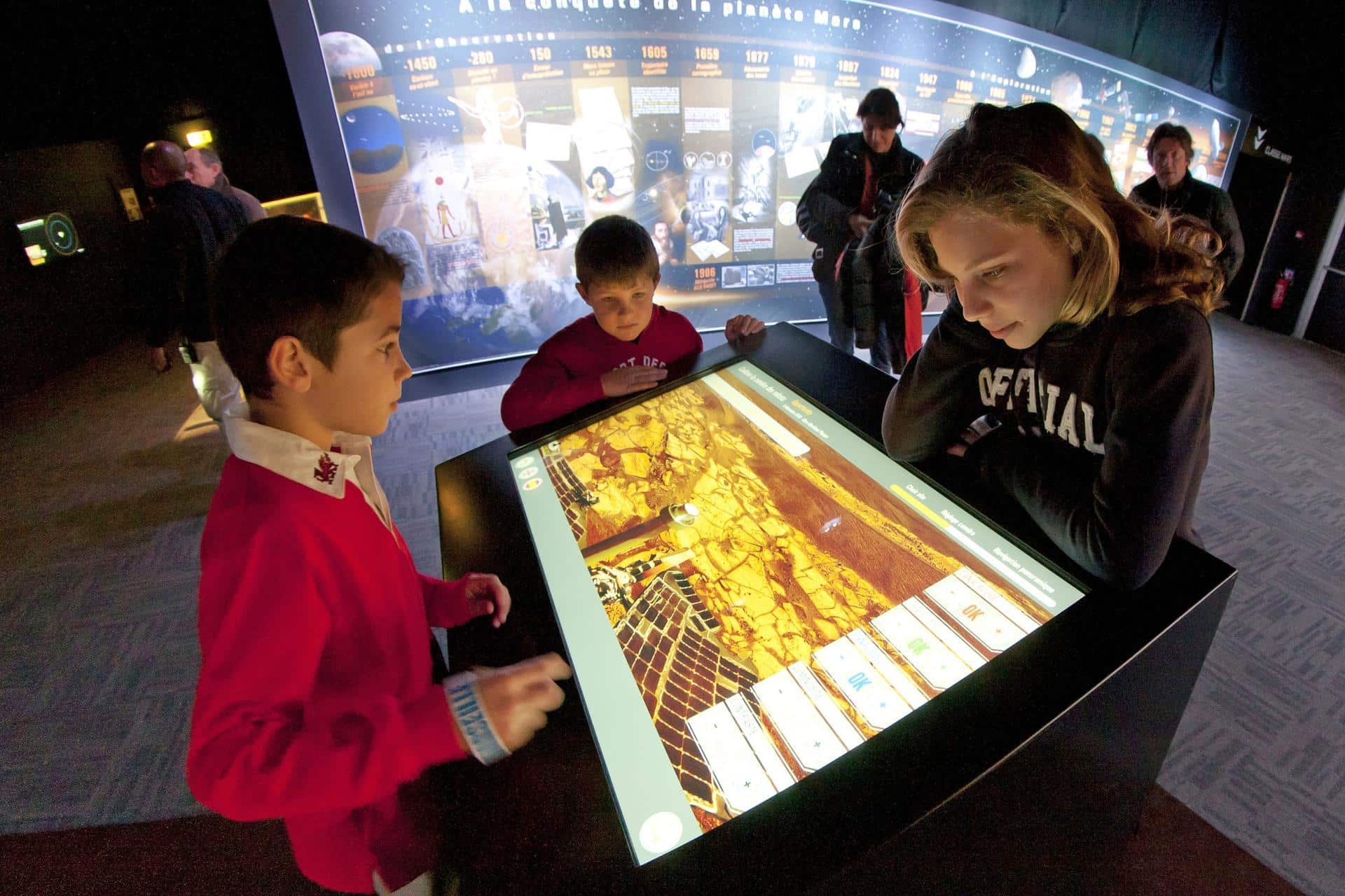 Enfants autour d'un écran tactile dans l'exposition Explore Mars
