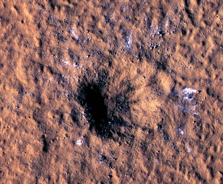 Le cratère de 150 m de large creusé par l’impact de l’astéroïde du 24 décembre 2021 sur Mars. En blanc : les blocs de glace d’eau arrachés au sous-sol. Crédit : NASA/JPL-Caltech/University of Arizona